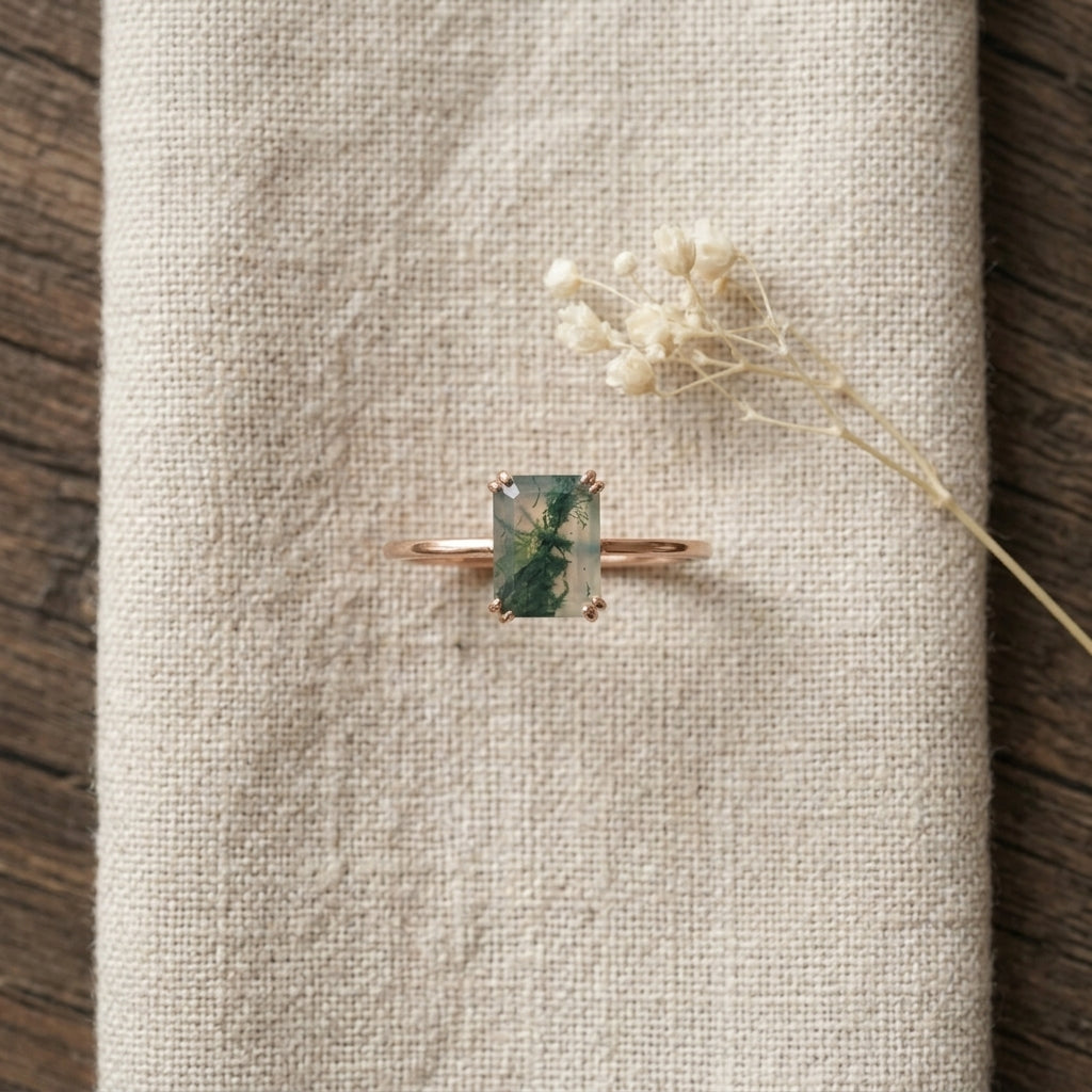 Emerald Cut Moss Agate Solitaire Ring Kepp on table