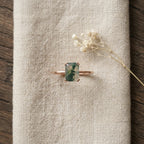 Emerald Cut Moss Agate Solitaire Ring Kepp on table